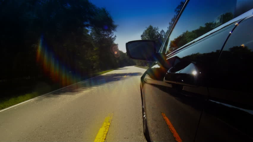 Timelapse of car driving down narrow road