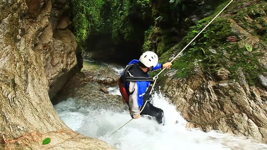 Adult man desceding a waterfall in Ecuadorian rain forest 