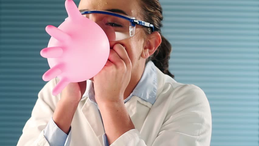 Pretty woman is a Science laboratory intern messing about blowing up pink balloon
