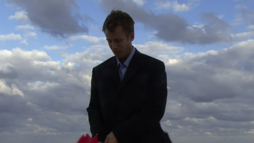 Cu of a male opening an umbrella on a beach and checking if it is raining