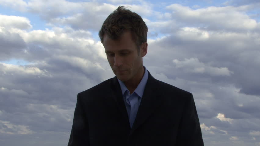 Cu of a male opening an umbrella on a beach and checking if it is raining