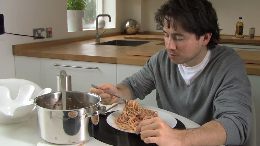 MEDIUM SHOT PAN OF A MAN EATING PASTA
