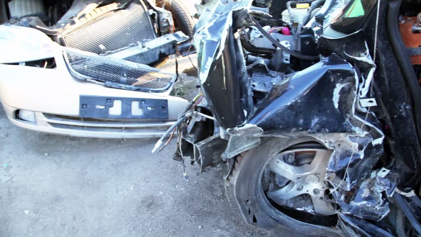 Several crashed cars stand on junkyard, closeup view in motion