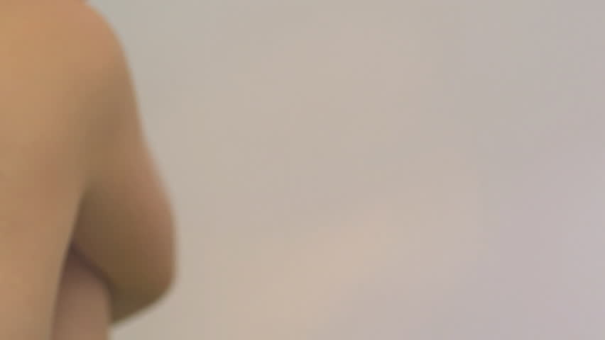 CLOSE UP PAN OF A YOUNG WOMAN MOISTURIZING ON WHITE BACKGROUND