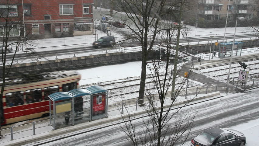 Tram drives away from a tram stop with snow everywhere