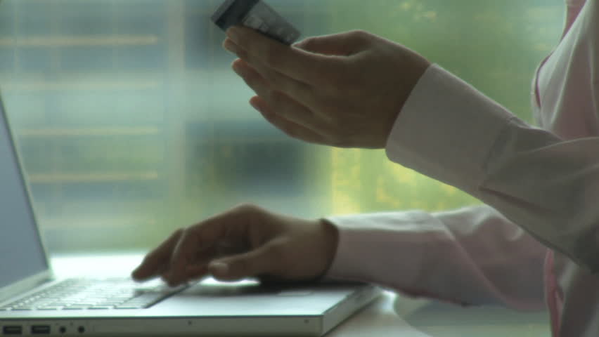 MEDIUM SHOT PAN FEMALE DOING CREDIT CARD TRANSACTION ON LAPTOP 