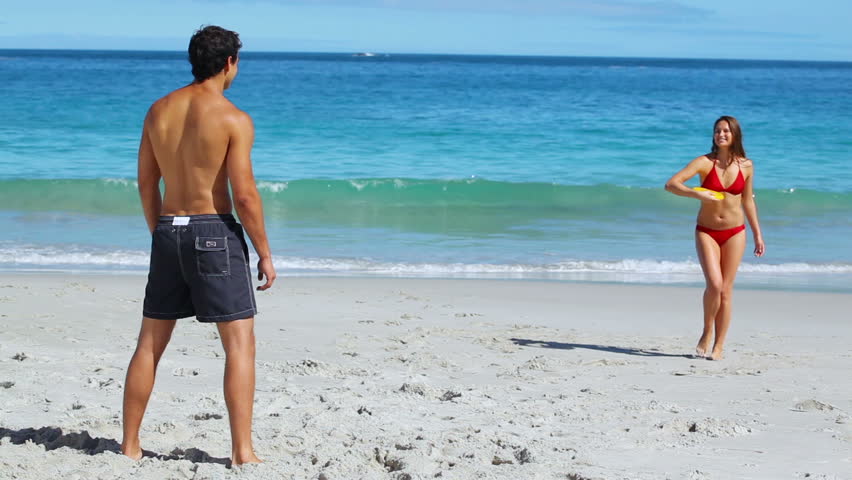 Active couple playing with a sport disc on the beach