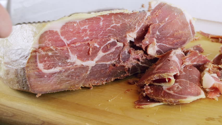 Ham Leg Carved Horizontal (HD). Boneless Pork Serrano or prosciutto ham leg carved on a wood board on horizontal position. These ham "Jamon" legs are a Spanish delicacy. 