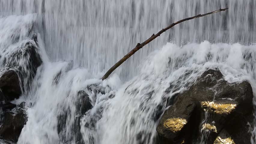 Waterfall cascading down rocks with old tree stuck