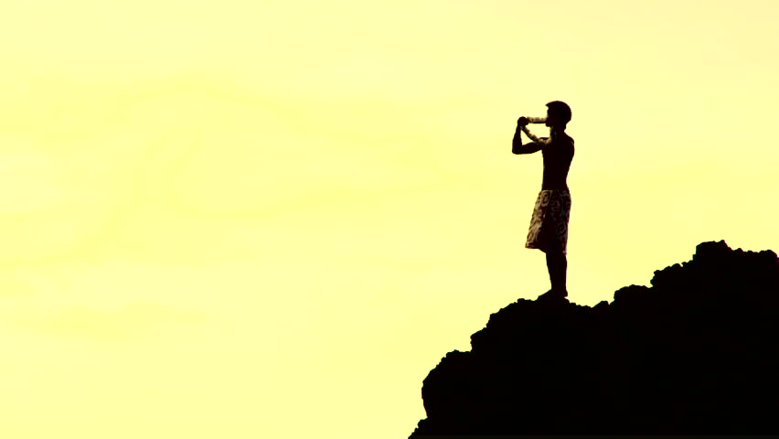Unrecognizable man on cliff in Maui, Hawaii throws flower lei into the ocean then swan dives off, into the Pacific, slow motion and treated.
