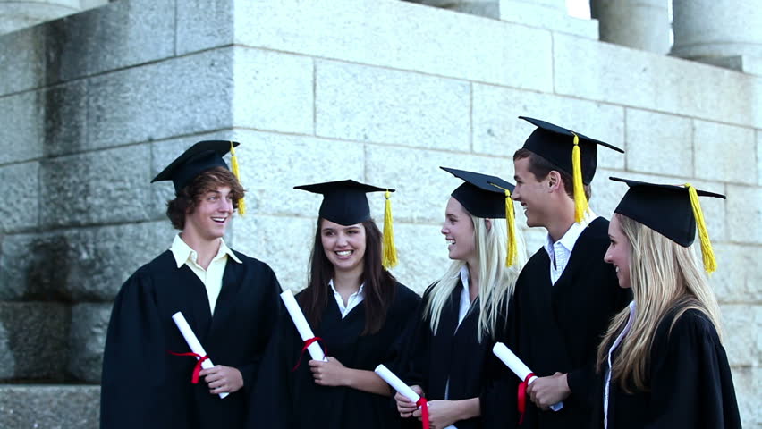 Graduates throwing mortar boards in the air while holding diploma