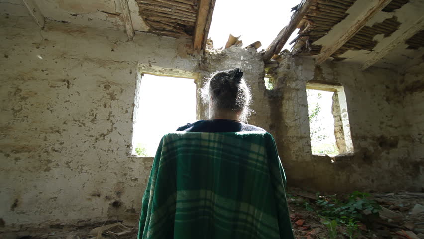 Senior woman looking out the window abandoned house, dolly shot, rear view