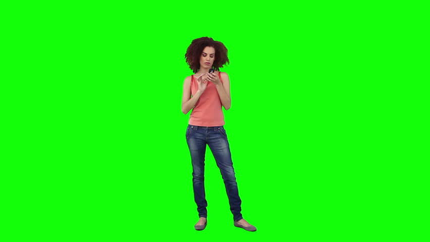 A woman is texting on her mobile phone against a green background