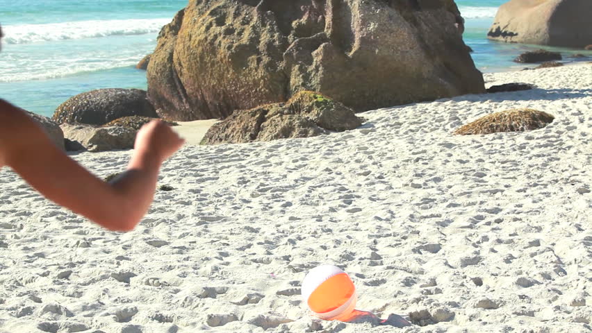 Two women running and taking an inflatable ball at the beach