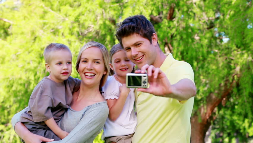 Family taking a picture with a digital camera in a park