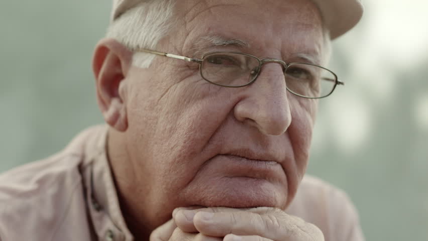 Seniors portrait, sad elderly man with white hat and glasses looking at camera