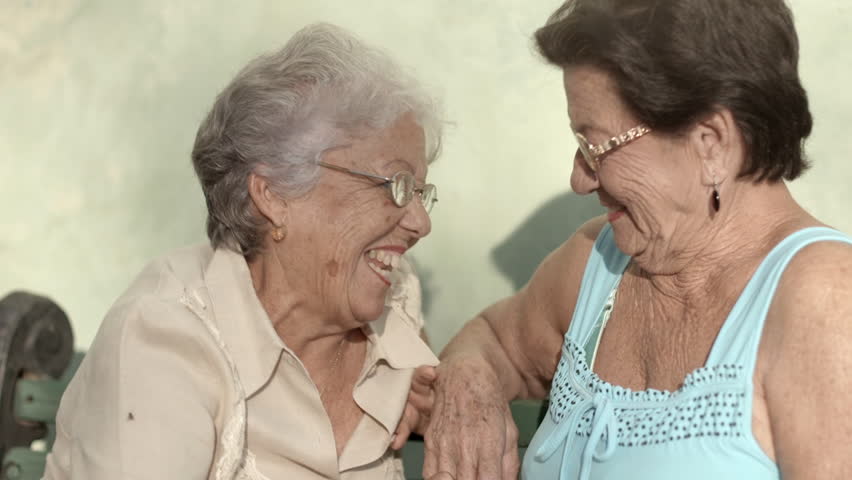 Active retirement and women, two elderly female friends talking on bench in public park