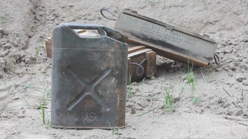 Person In Combat Boots And Camo Pants Pauses And Walks By Old Metal Can And Empty Wooden Crates