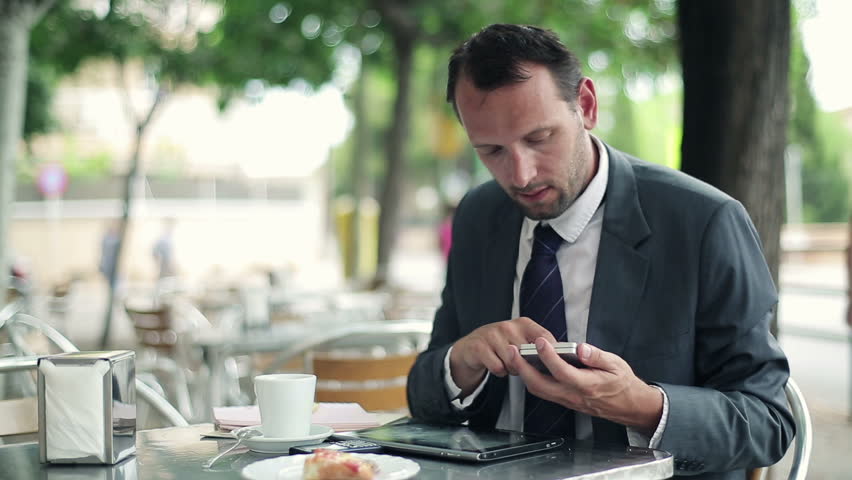 Businessman working with tablet and smartphone in cafe
