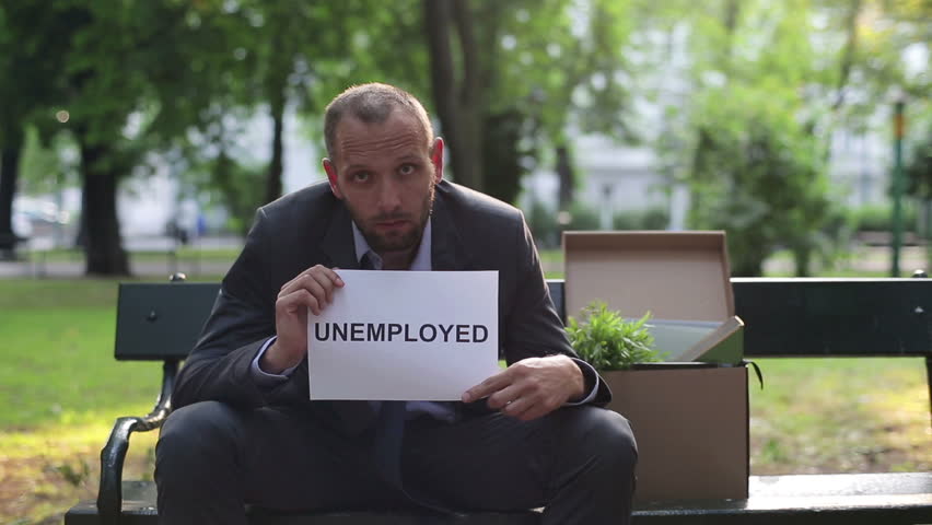 Just fired sad businessman holding paper sheet with "UNEMPLOYED" sign
