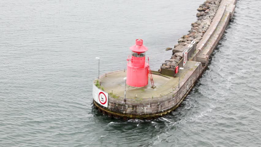 small beacon standing on platform in middle of water, flowed round by waves