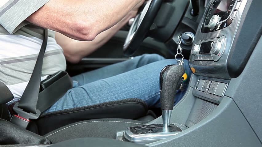 Man in car inserting ignition key, starting engine and switches the transmission to automatic gearbox