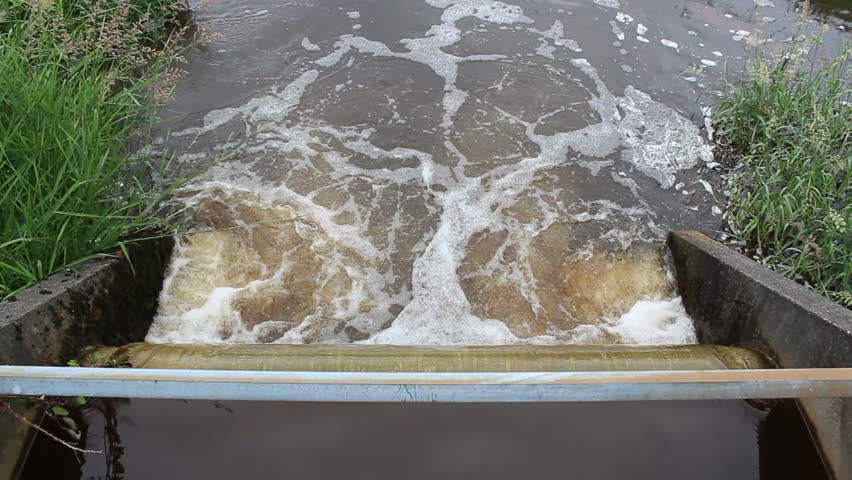 Water channels out of a levy and into a narrow stream used to irrigate farm lands/Water Levy Output/Water is dispersed into a channel by a water levy mechanism