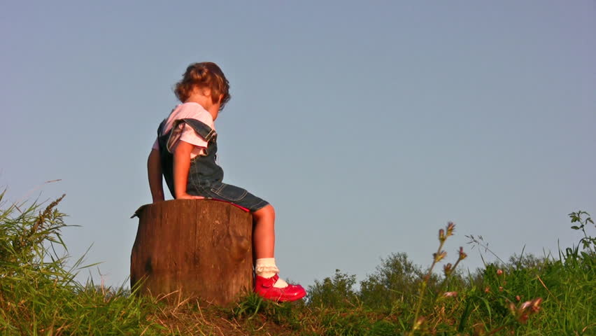 little girl climb on stump 