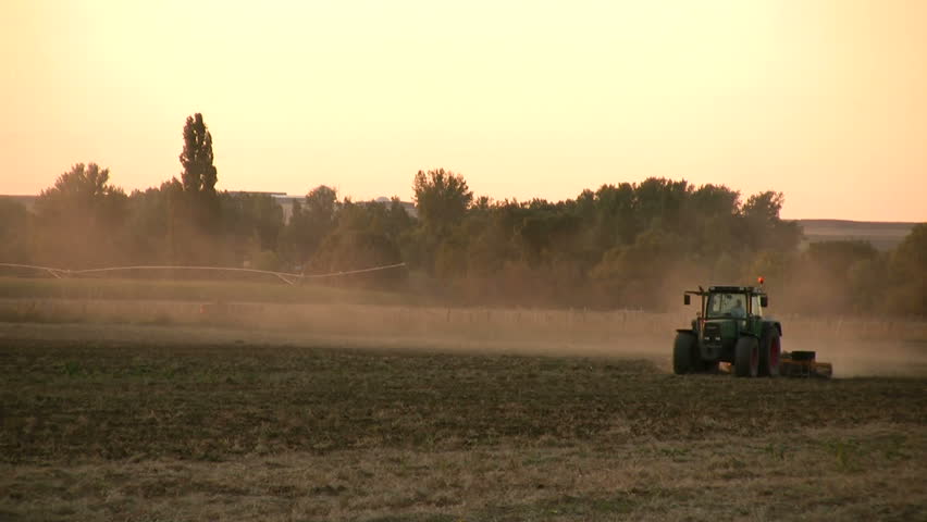 Tractor working in the field at sunset