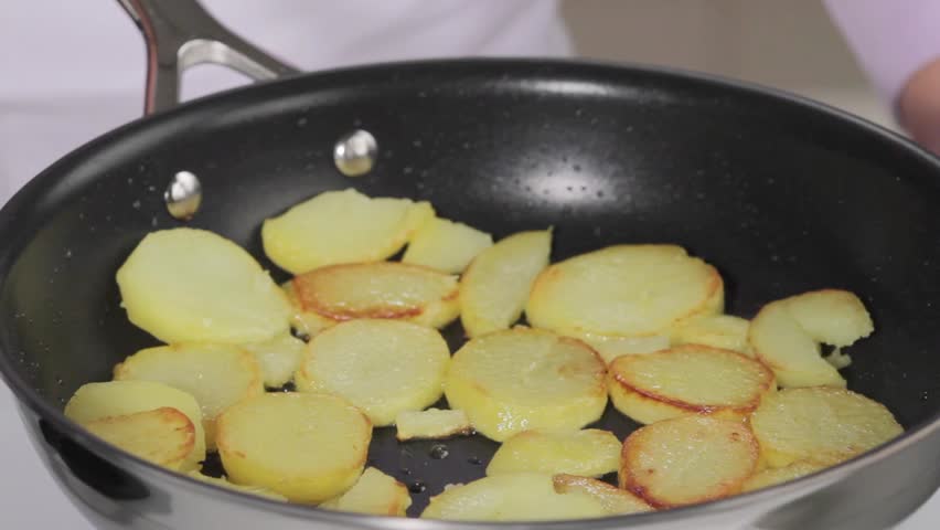 Potato slices being fried in a pan
