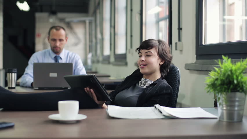 Happy businesswoman relaxing with tablet computer in the office

