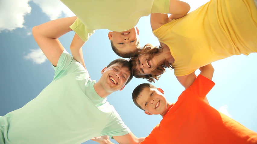 Parents and children hugging and looking at camera from above representing family support and unity, copy-space provided at the end
