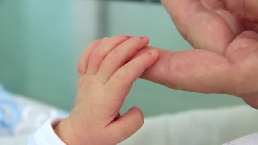 Mother and newborn daughter in maternity home. Hand in hand