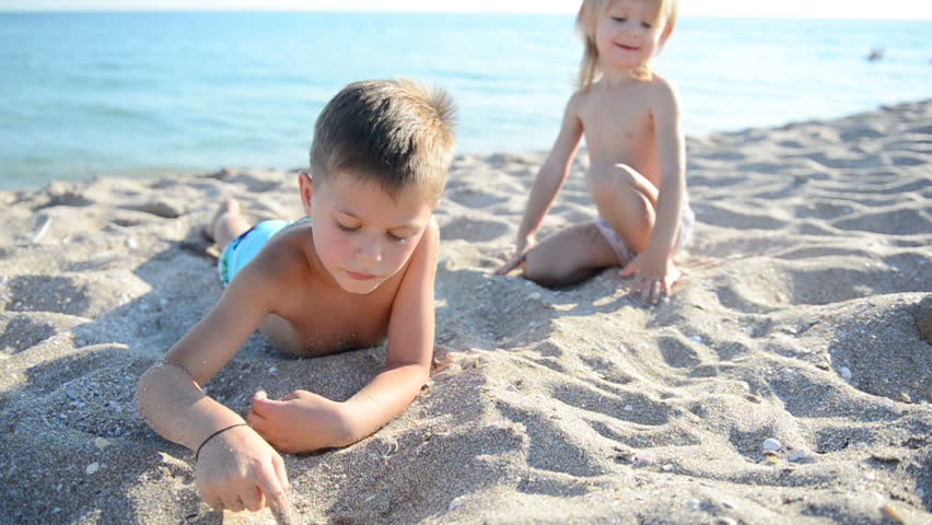 Children on a beach draw on sand
