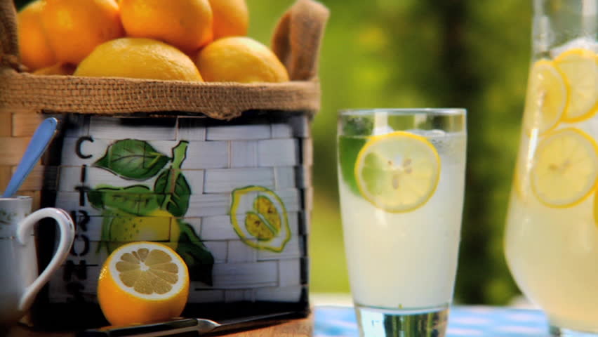 Man removing glass of lemonade from table outside