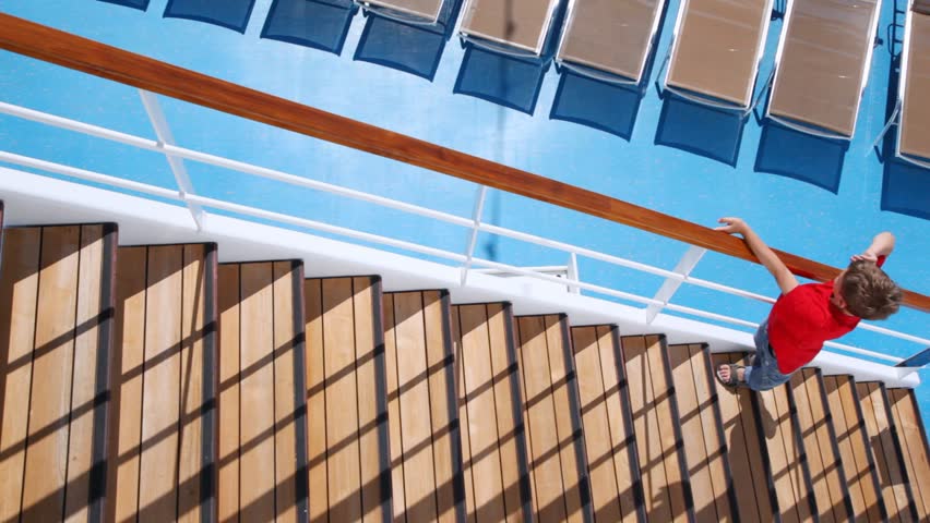 Boy in red T-shirt runs on ladder upwards on ship deck