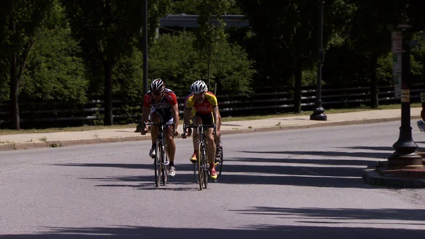 PROVIDENCE, RHODE ISLAND - SEPTEMBER 3, 2009: Three bicycle racers passing camera -- zoom to pedals and wheels - slow motion