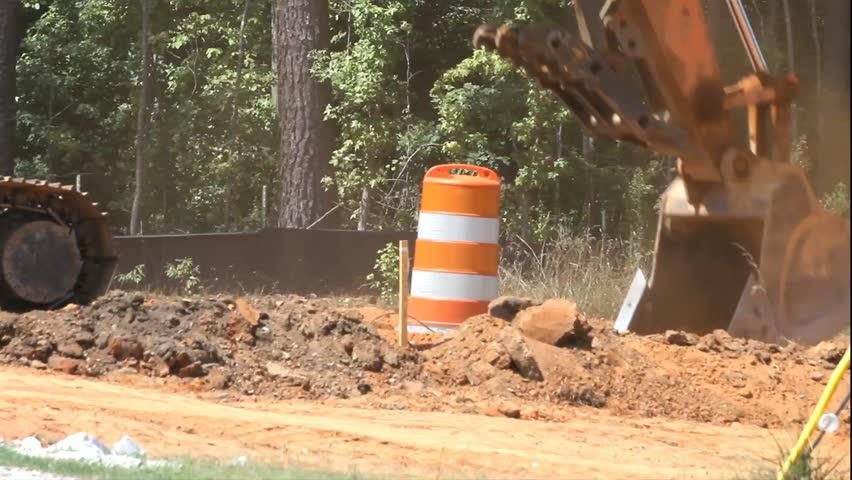 Excavator Bucket At Construction Site Lifts Dirt Then Taps Ground Repeatedly