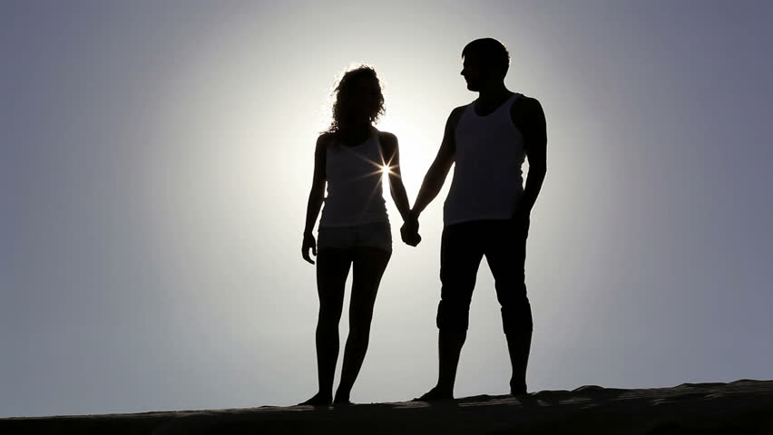 Happy couple embracing and kissing while sunset