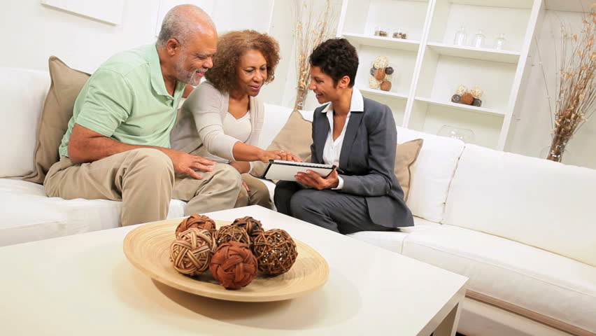 Elderly ethnic couple discussing investments home financial advisor with laptop