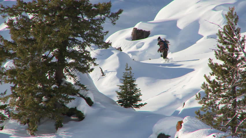 SLOW MOTION - Male snowboarder making steep back-country powder turns