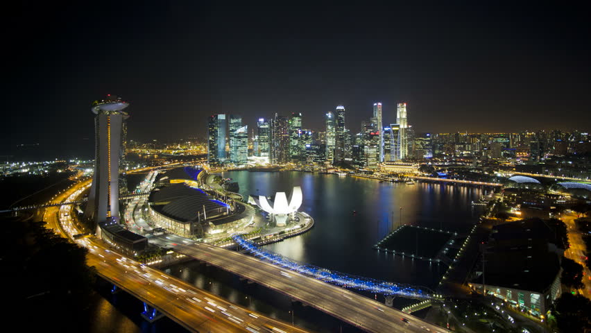 Elevated illuminated downward view over the City Centre and Marina Bay at dusk