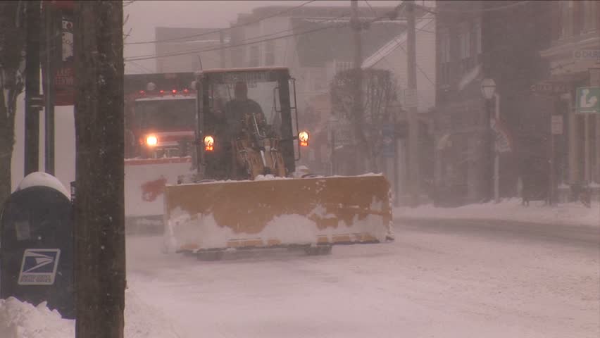 NEW ENGLAND - CIRCA JANUARY 2006: Snowplows driving along snowy downtown street