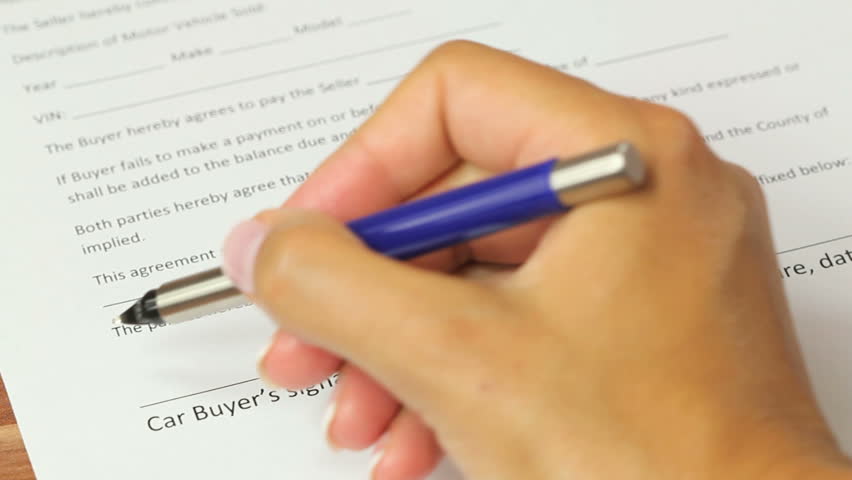 Car Buyer Signature - Female signing a contract for purchase of a car, closeup of a car buyer signature on a blank car sales document