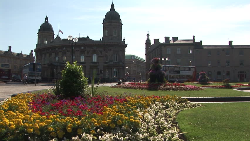 Water fountains with flowers in city square with double-decker buses Hull, UK