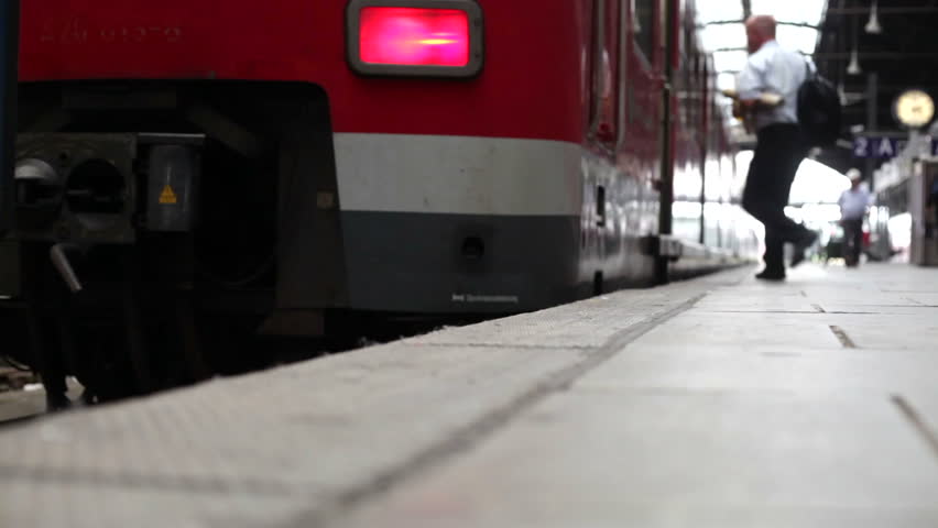 :A middle-aged businessman with luggage is boarding a suburb train of german railroad company DB at the railroad station of Wiesbaden on August 08, 2012