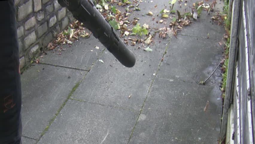 Road service man sweeping leaves and debris with gas petrol engine portable air blower