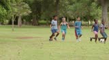 Multiethnic boys and girls playing european football/ american soccer in city park. Summer camp fun. Slow motion. 