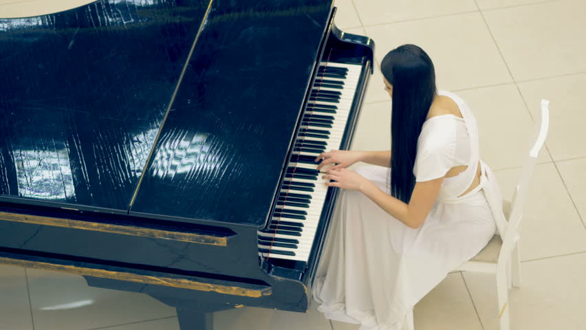 Высокая пианистка в прозрачной юбке возле белого рояля