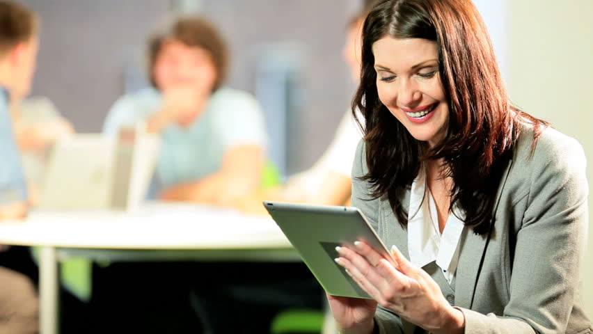 Portrait of female young lecturer e-learning on tablet diverse classmates in campus IT library
